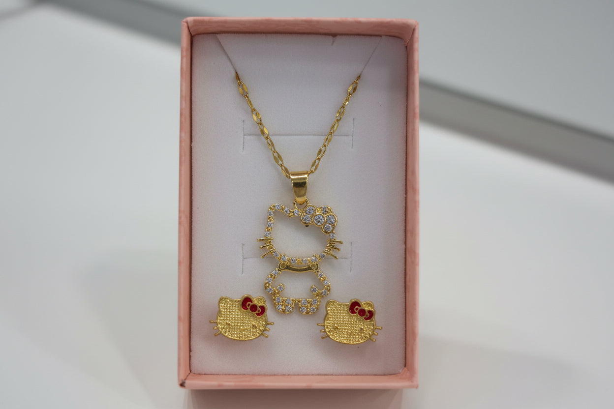 Gold jewelry set with necklaces and pendants in a box held by a hand.